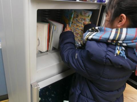 子供が図書除菌機に本を立てている様子